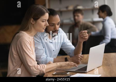 Happy concentrated two young mixed race employees working on computer. Stock Photo