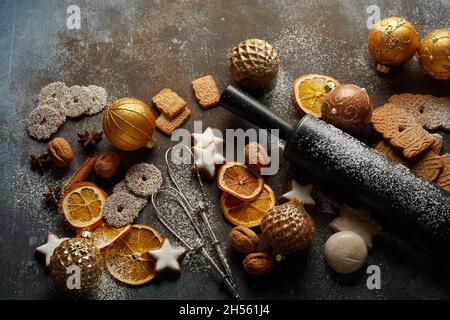Cookies, Christmas tree balls, baking tools, dry oranges, and nuts on the table Stock Photo