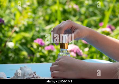 Essential oil dropping from leaf to the bottle. Essence liquid cosmetic. Perfume.Aromatherapy. Isolated on white. Stock Photo