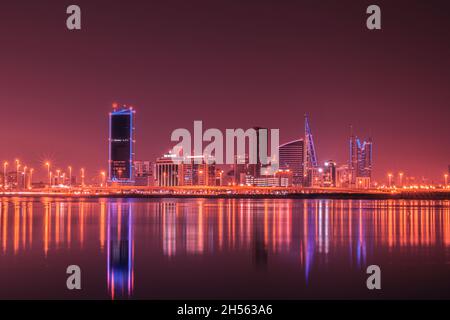 Night modern city skyline with neon lights and reflection in the water. Manama, the Capital of Bahrain, Middle East Stock Photo