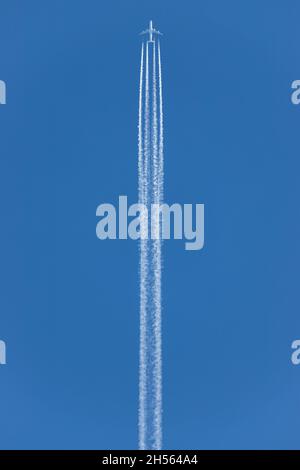 engine exhaust contrails behind an four-engined commercial aircraft flying at high altitude Stock Photo