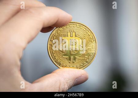 Bitcoin cryptocurrency coin held between two fingers Stock Photo