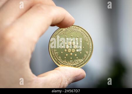 Cardano Ada coin held between two fingers Stock Photo