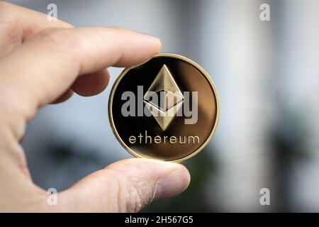 Ethereum cryptocurrency physical coin held between two fingers Stock Photo