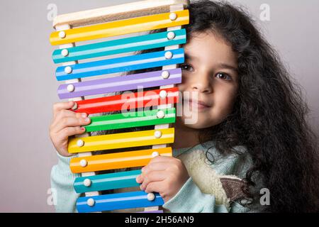 Little girl portrait with xylophone in hand looking in camera with expression, childhood memories Stock Photo