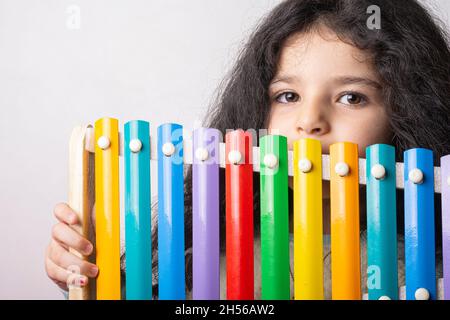 Little girl portrait with xylophone in hand looking in camera with expression, childhood memories Stock Photo