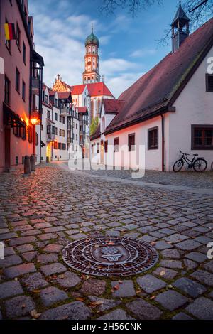 Augsburg, Germany. Cityscape image of old town street of Augsburg, Germany with the Basilica of St. Ulrich and Afra at autumn sunset. Stock Photo