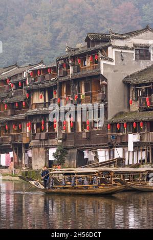 Hunan, China, 14 Nov 2011: Man rowing wooden boat along river of ancient street. Stock Photo