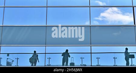 Reflection of people in windows of airport terminal on blurred window Stock Photo