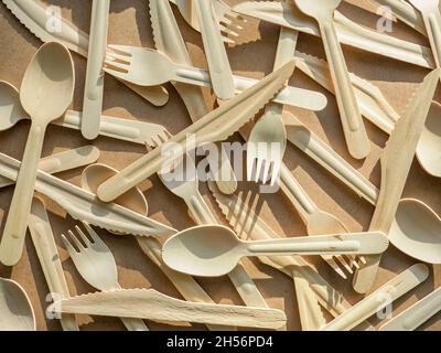 eco friendly disposable kitchenware utensils on craft paper background. Wooden forks, knives and spoons. Ecology, zero waste concept. top view. flat Stock Photo