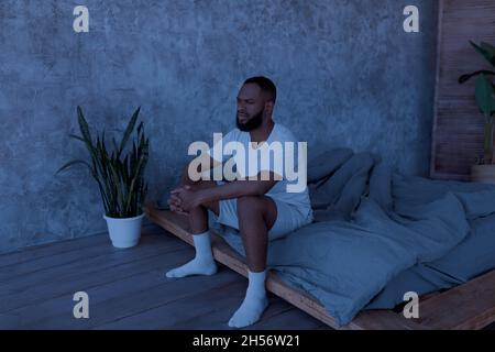 Black man sitting on bed and thinking Stock Photo