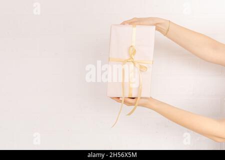 Women's hands are wrapping a Christmas present in silver wrapping paper.  Stock Photo by AllaRudenko