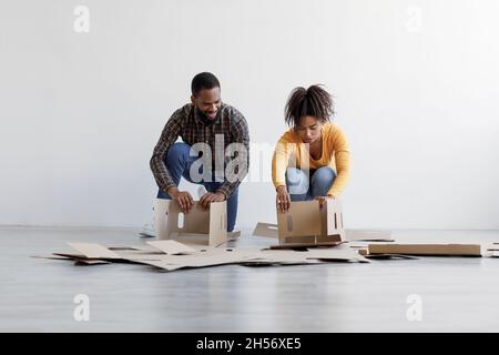 Young black family stack cardboard boxes and prepare to moving to new home. Renovation, relocating and buying new house Stock Photo