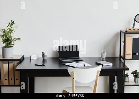 Minimal background image of opened laptop at desk in home office in black and white interior, copy space Stock Photo