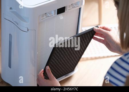 Woman removes filter from air purification system Stock Photo