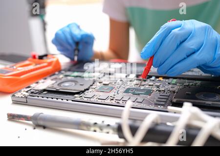 Laptop repair, hands hold voltage meter for electronics Stock Photo