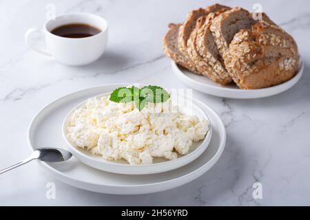 A bowl with fresh cottage cheese, rye bread and coffee on the table.  Stock Photo