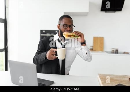 Black man rushing to work eating sandwich at home Stock Photo