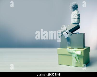 Pastel green and grey gift boxes  with winter wool hat on top , white background. Selective focus. Stock Photo