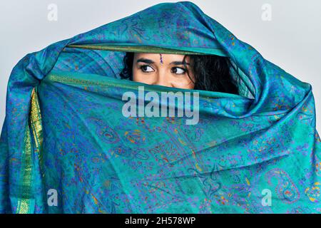 Young indian woman wearing sari covering head and face, doing elegant pose with traditional scarf Stock Photo