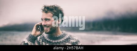 Phone man in winter calling someone on cellphone walking outside panorama banner. Young smiling model holding smartphone in Iceland background Stock Photo