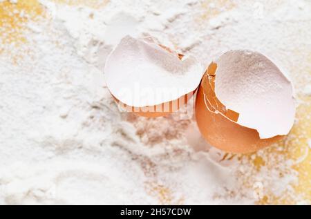 Broken eggshell with flour on yellow background Stock Photo