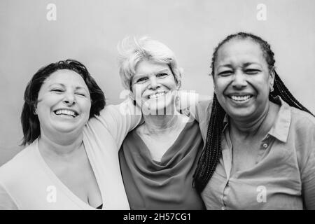 Happy diverse senior people hugging each other outdoor - Older friends community concept - Black white edition Stock Photo