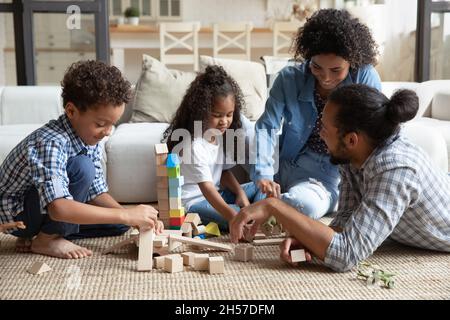 Happy family couple and little sibling kids constructing toy castle Stock Photo