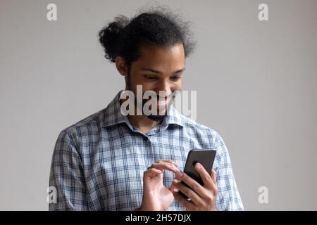 Happy millennial Black guy reading text message on mobile phone Stock Photo