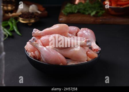 Raw chicken biriyani cut without skin arranged on black container with cooking ingrediants placed nearby. Stock Photo