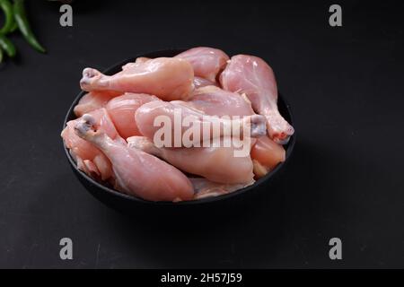 Raw chicken biriyani cut without skin arranged on black container with cooking ingrediants placed nearby. Stock Photo