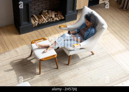 Relaxed young African American woman resting in comfortable armchair Stock Photo