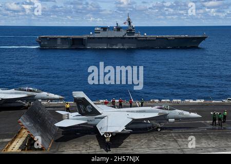 South China Sea, United States. 30 October, 2021. A U.S. Navy F/A-18 fighter jet prepares to launch from rom the flight deck of the Nimitz-class aircraft carrier USS Carl Vinson as the Japan Maritime Self- Defense Force Izumo-class helicopter destroyer JS Kaga sails alongside during joint operations October 30, 2021 in the South China Sea.  Credit: MC3 Tyler Wheaton/U.S. Navy/Alamy Live News Stock Photo