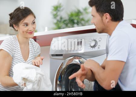 man and woman hanging laundry on clothing rack Stock Photo