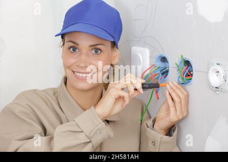 female electrician fixing electric cables in socket Stock Photo