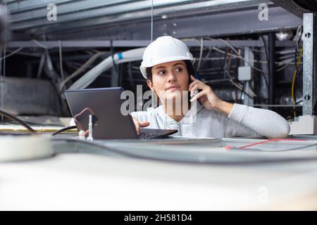 female contractor using laptop in roofspace Stock Photo