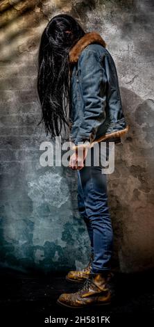 Black long hair man with jeans and big yellow shoes and old wall Stock Photo