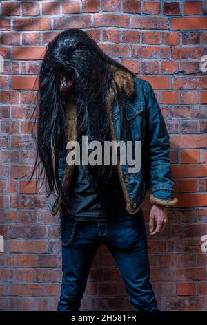 Black long hair man with jeans and big yellow shoes and old wall Stock Photo