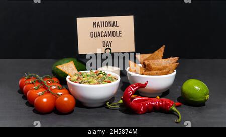The ingredients for making Spicy Guacamole are avocado, red onion, tomato, chili, lime, cilantro, and garlic. National Guacamole Day. Stock Photo