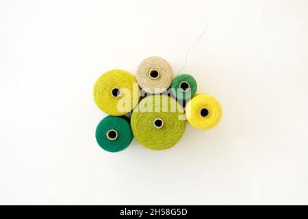 Arrangement of threads in shades of green, white background, flat lay. Equipment to creative project concept, DIY, hobby, design works. Colourful cord Stock Photo