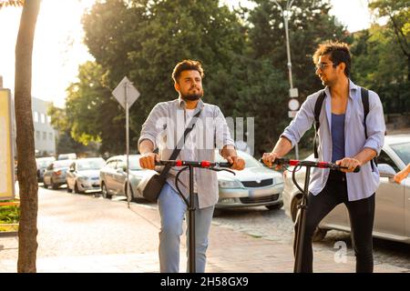 Two adult students stand in the city with electric scooters Stock Photo