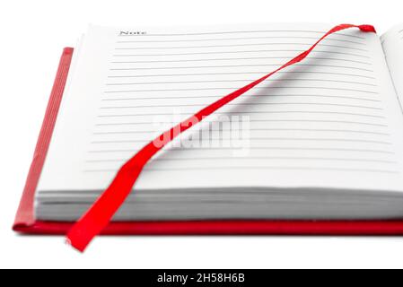 Open red notebook with black lines with ribbon, isolated on a white background. Stock Photo