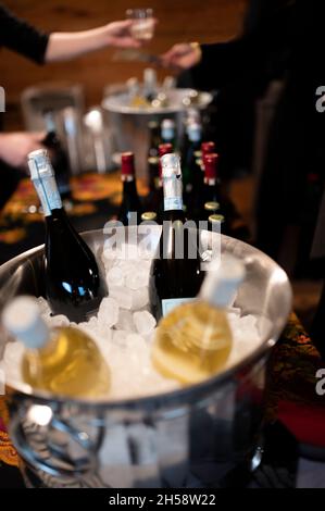a person being given a glass of red wine at a party with wine being chilled in an ice bucket Stock Photo
