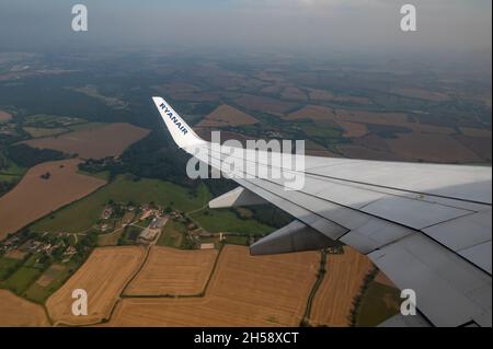 06/09/2021. Commercial Ryanair airborne airplane at high altitude. Cabin window view at wing with trademark name. Stock Photo