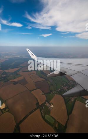 06/09/2021. Commercial Ryanair airborne airplane at high altitude. Cabin window view at wing with trademark name. Stock Photo