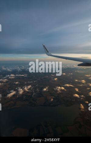 06/09/2021. Commercial Ryanair airborne airplane at high altitude. Cabin window view at wing with trademark name. Stock Photo