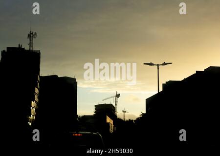 Residential and commercial buildings in silhouette from the yellow sunset. Building under construction. Salvador, Bahia, Brazil. Stock Photo