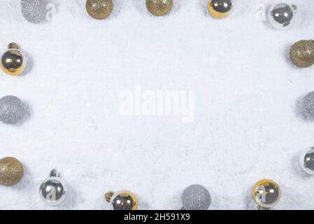 Colorful layout made of Christmas tree silver and gold baubles on snowy background. Flat lay, top view. Minimal abstract winter holidays concept. Stock Photo