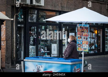 Picture of a white caucasian woman, an old ice cream seller in belgrade, serbia, working and serving ice cream at night while wearing a respiratory fa Stock Photo