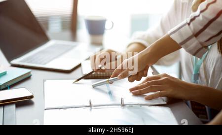Cropped image of Two businesswomen discuss and voting business strategy plan for the next project. pen pointing on papers Stock Photo
